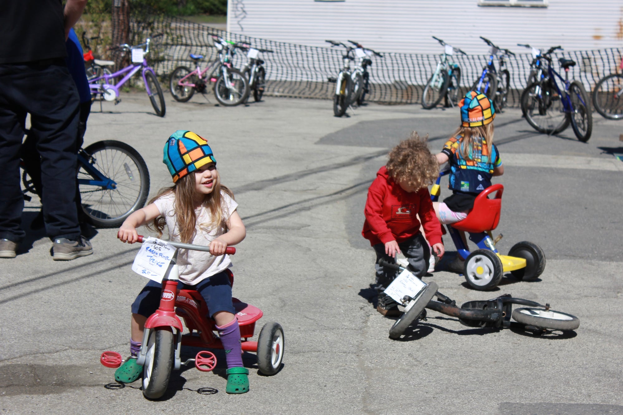 Three kids riding tricycles at a bike swap