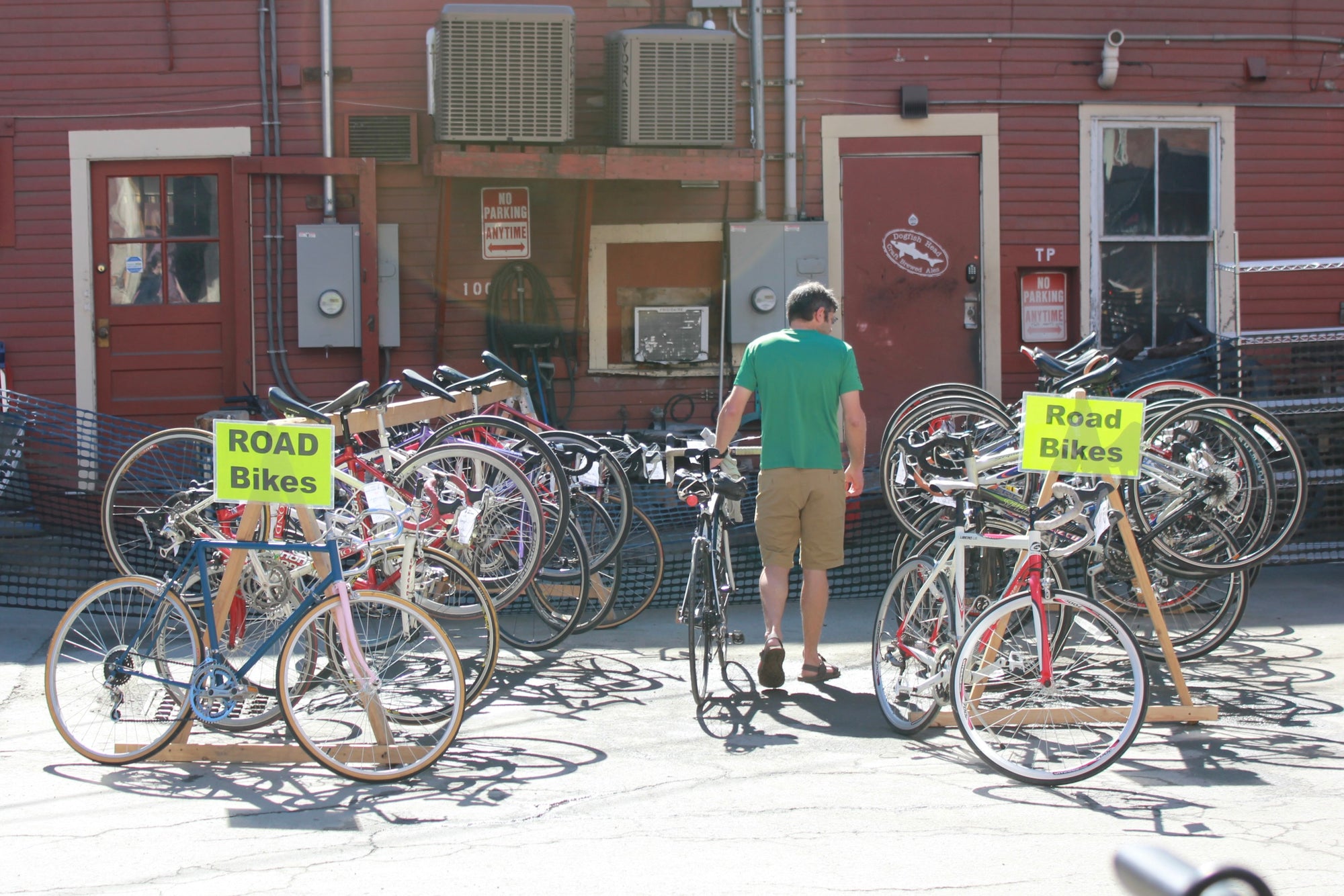 A person in a green shirt looking at two racks of used road bikes 