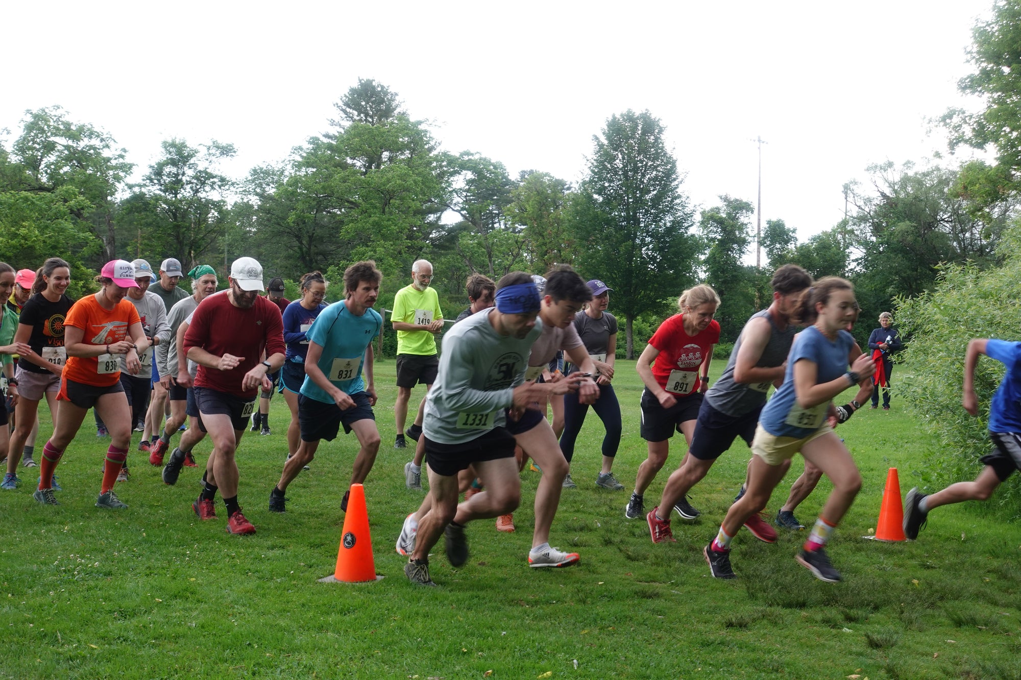 A group of 30 runners starting a race in a green, grassy field