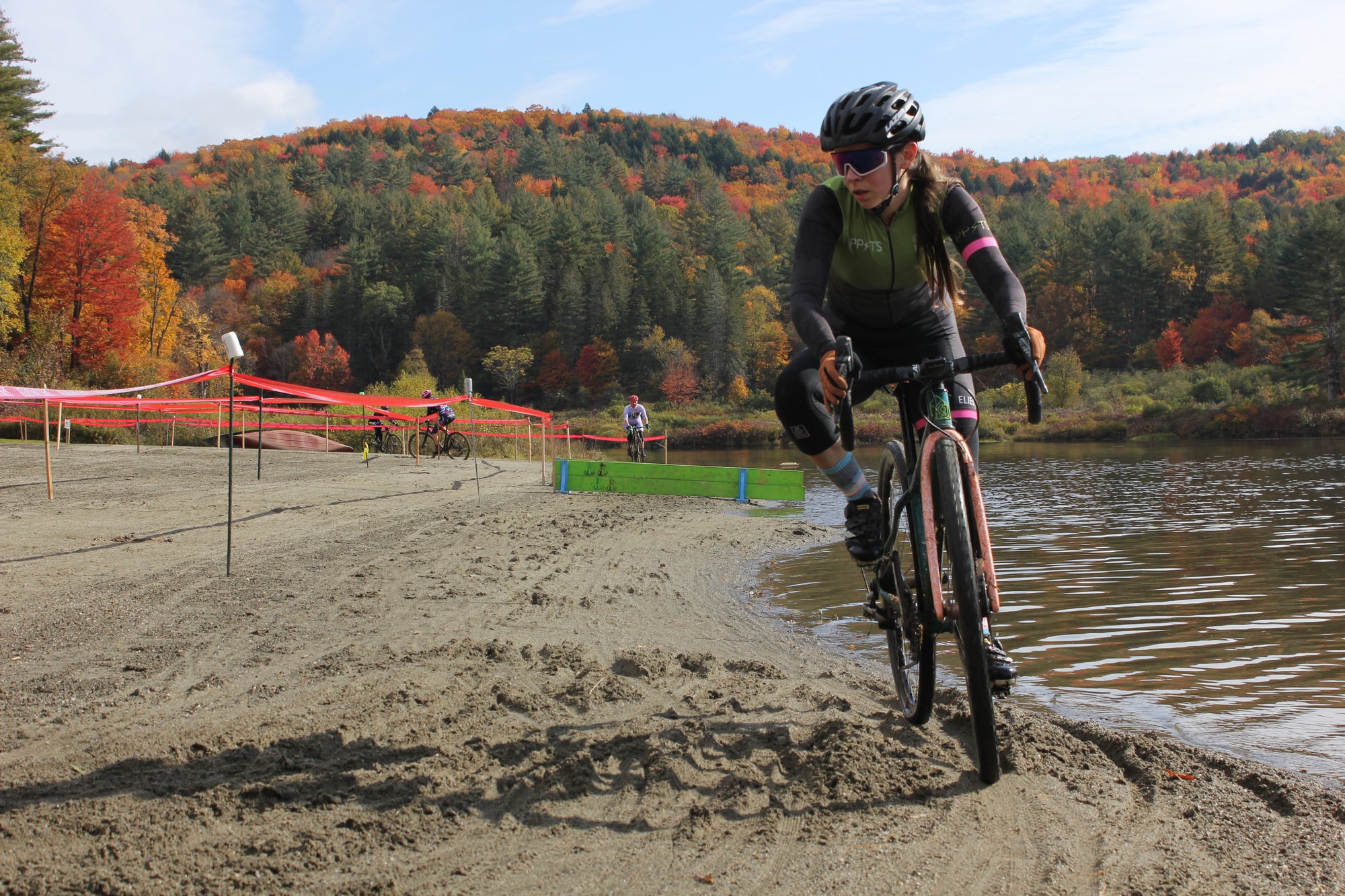 A cyclist on a beach by a lake racing cyclocross 
