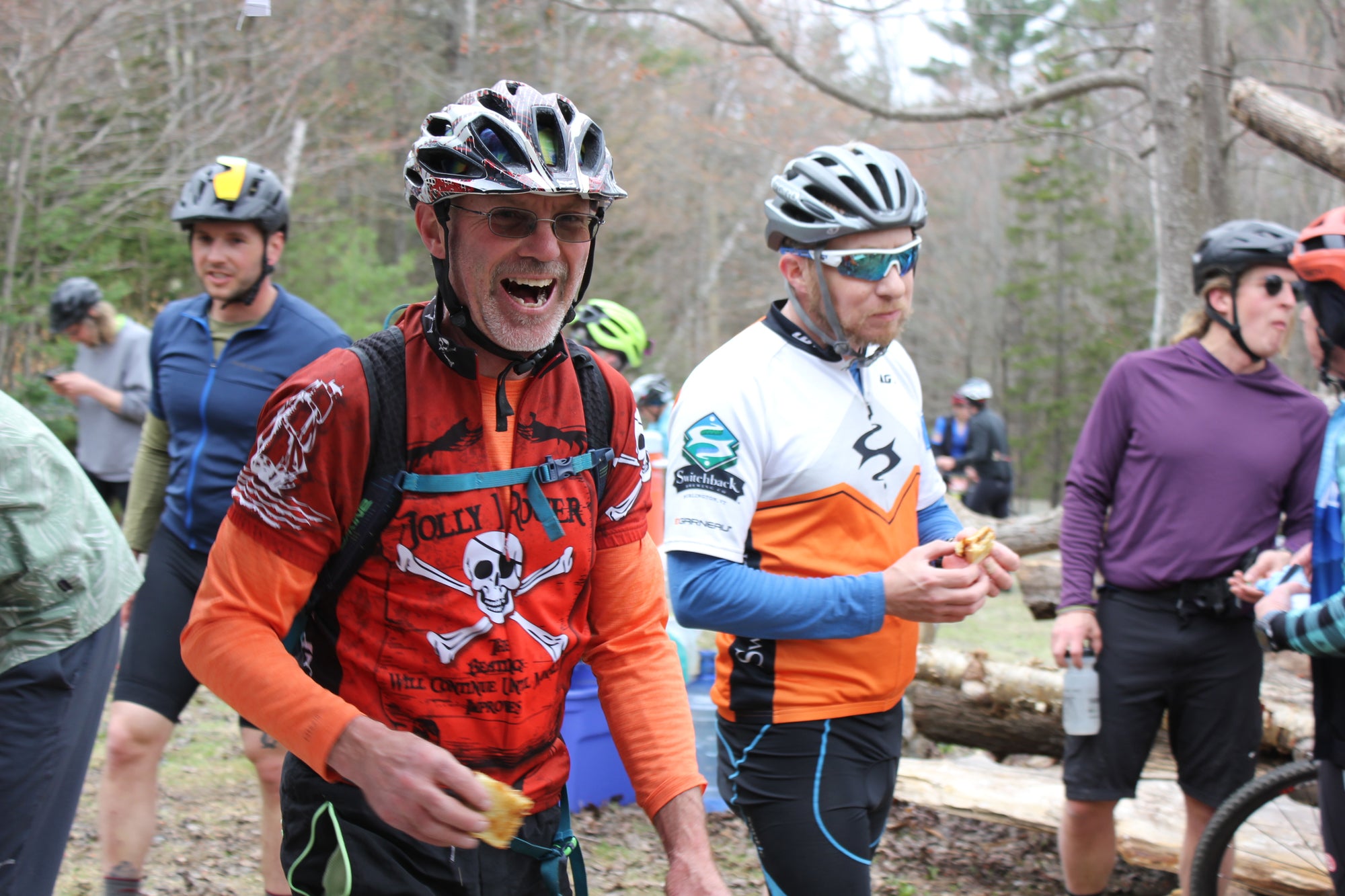 A cyclist in an orange jersey with a skull and crossbones on it