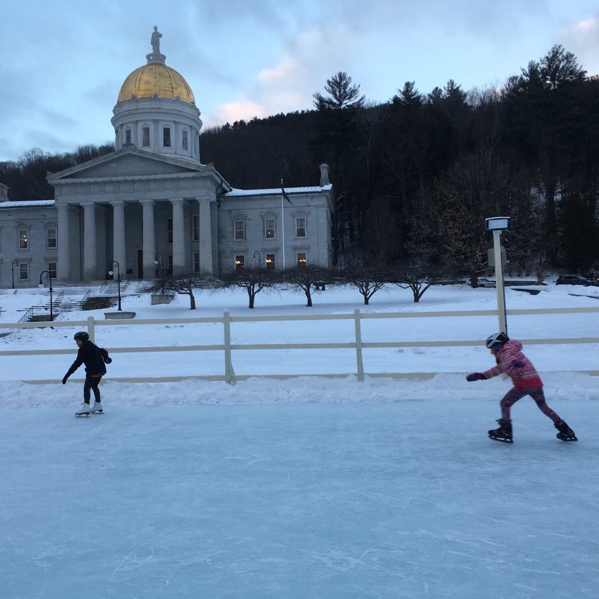 two kids ice skating in front of the Montpelier State House