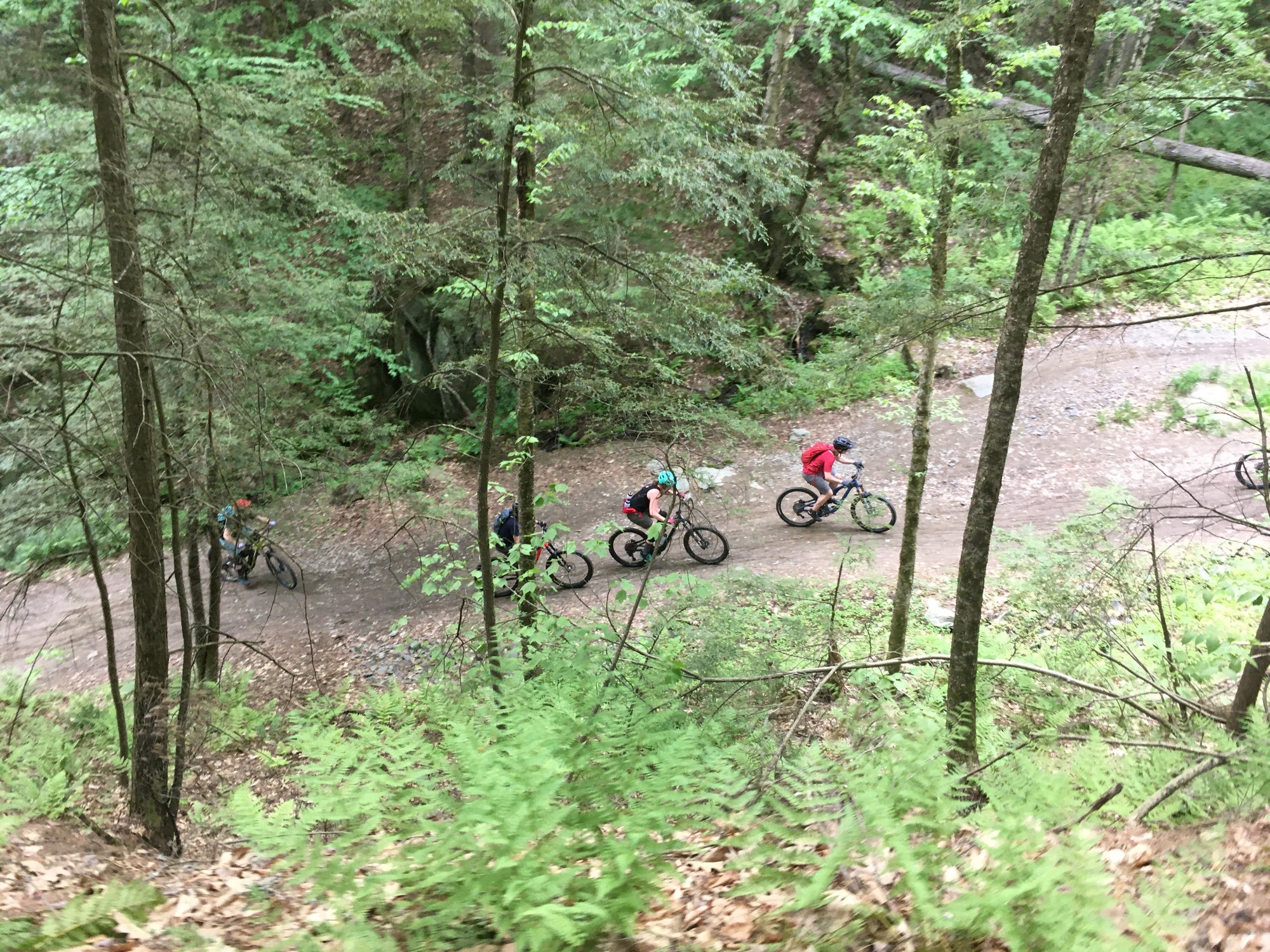 looking down on three mountain bikers riding on a trail below