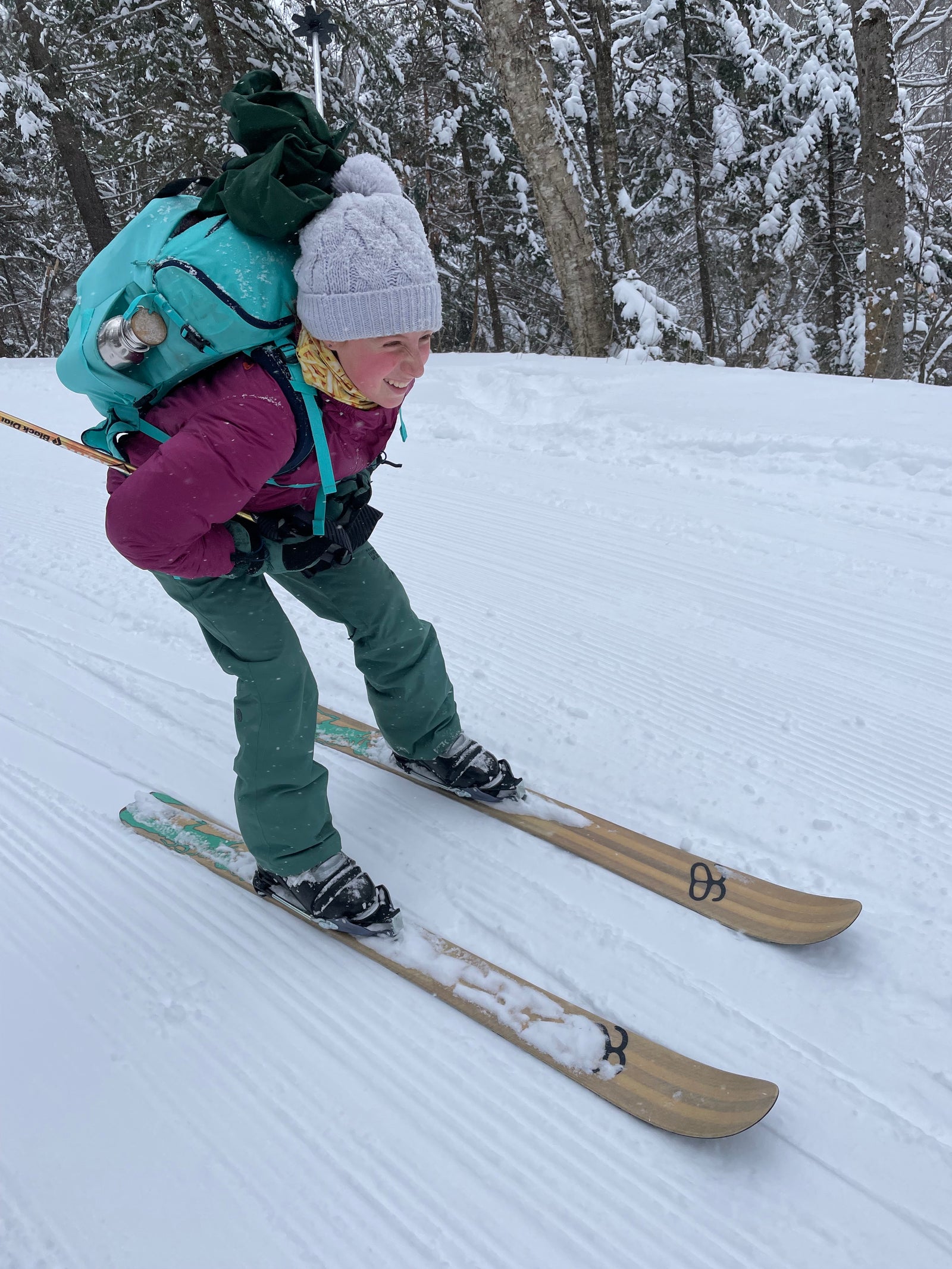A person in a purple jacket skiing downhill on a pair of Altai skis