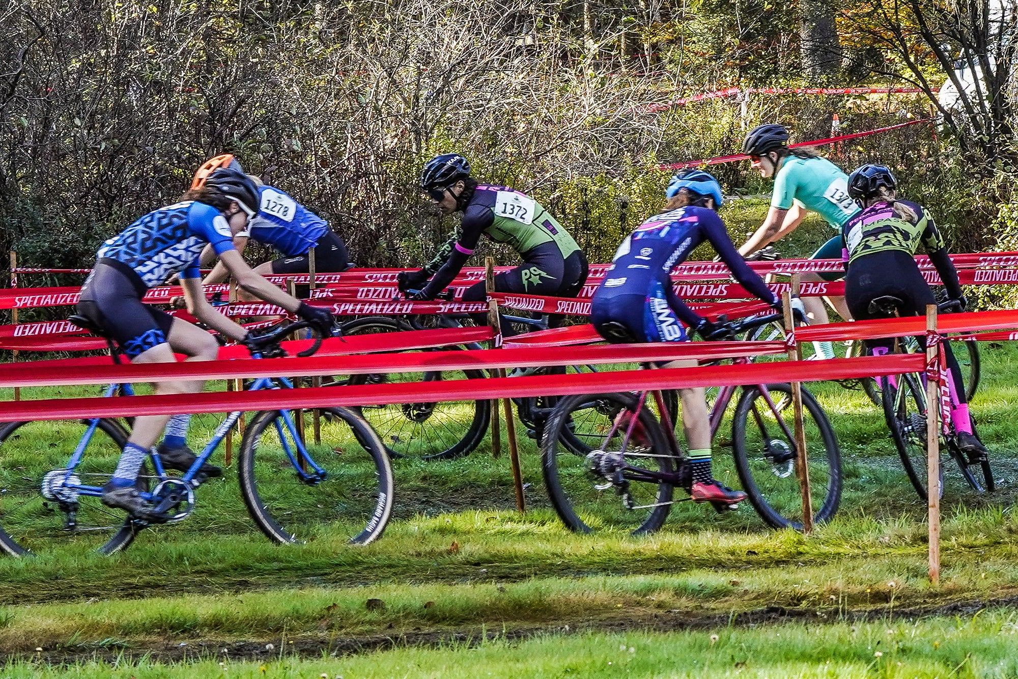 Bike riders racing cyclocross on a grassy field
