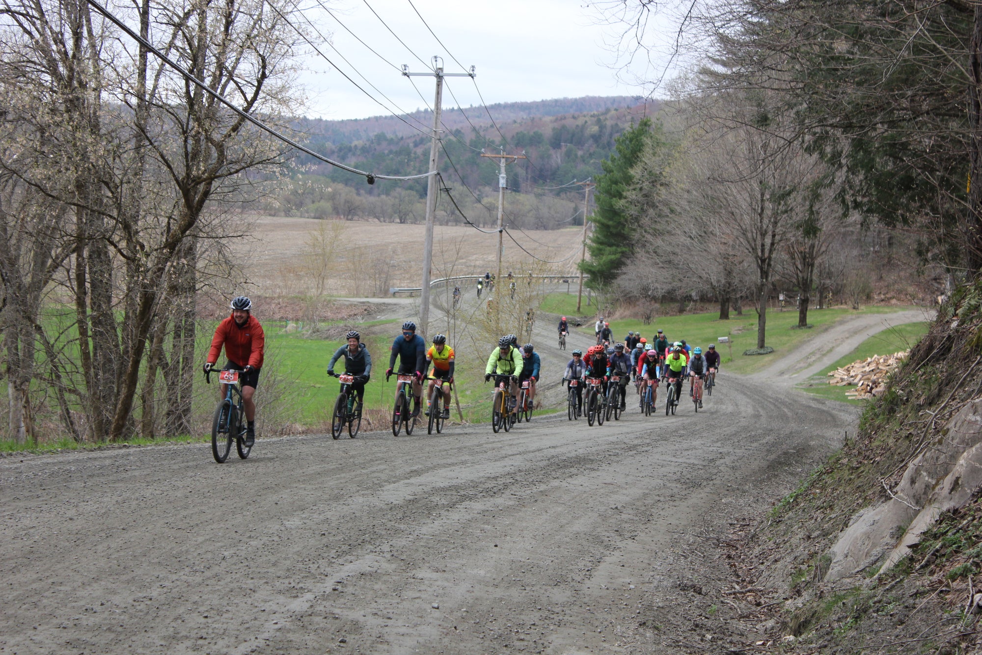 A large group of cyclists riding a dirt road