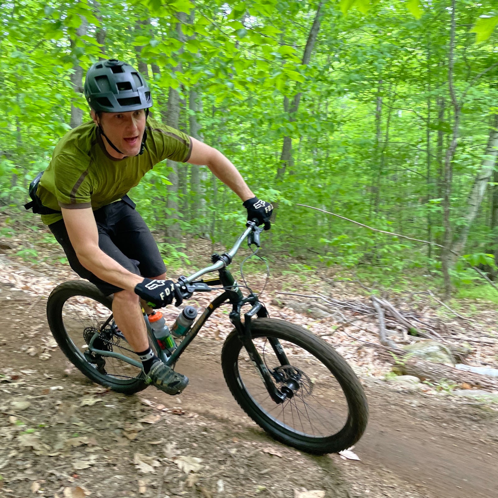 A mountain biker in a green t-shirt riding a downhill corner