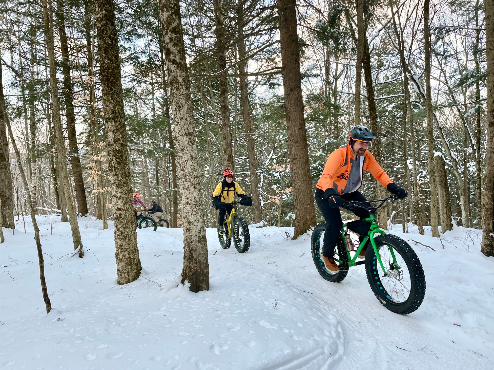 A person riding a fat bike on a snow packed trail in the woods